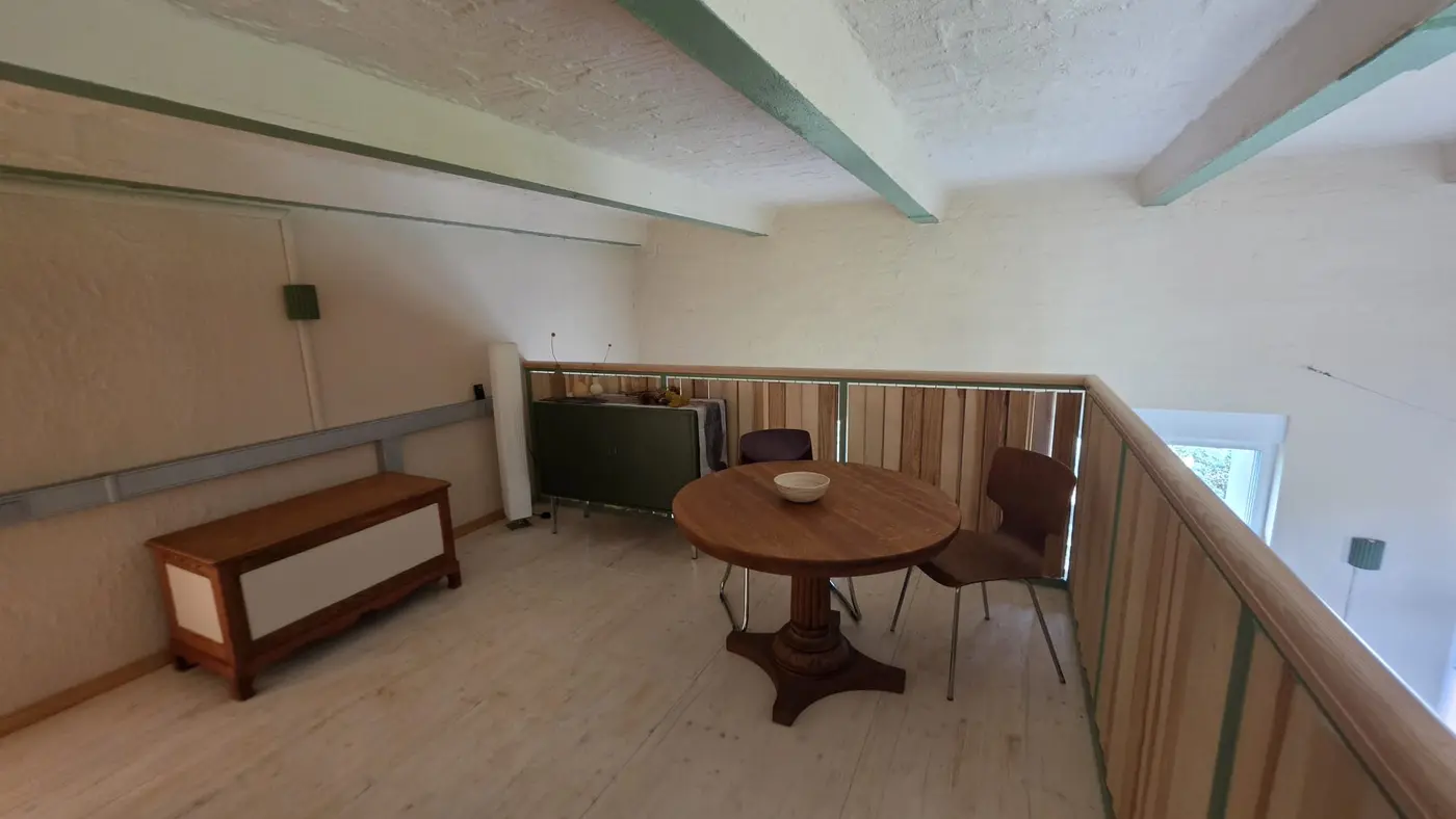 Sitzplatz auf der Galerieebene der Ferienwohnung Zahna-Loft — runder Tisch mit zwei Stühlen, Bank und Sideboard