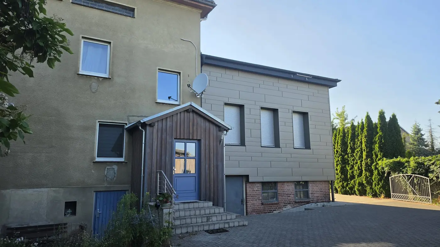 Außenansicht des Hauses der Ferienwohnung Zahna-Loft — Hofseite mit hölzernem Anbau und blauer Tür