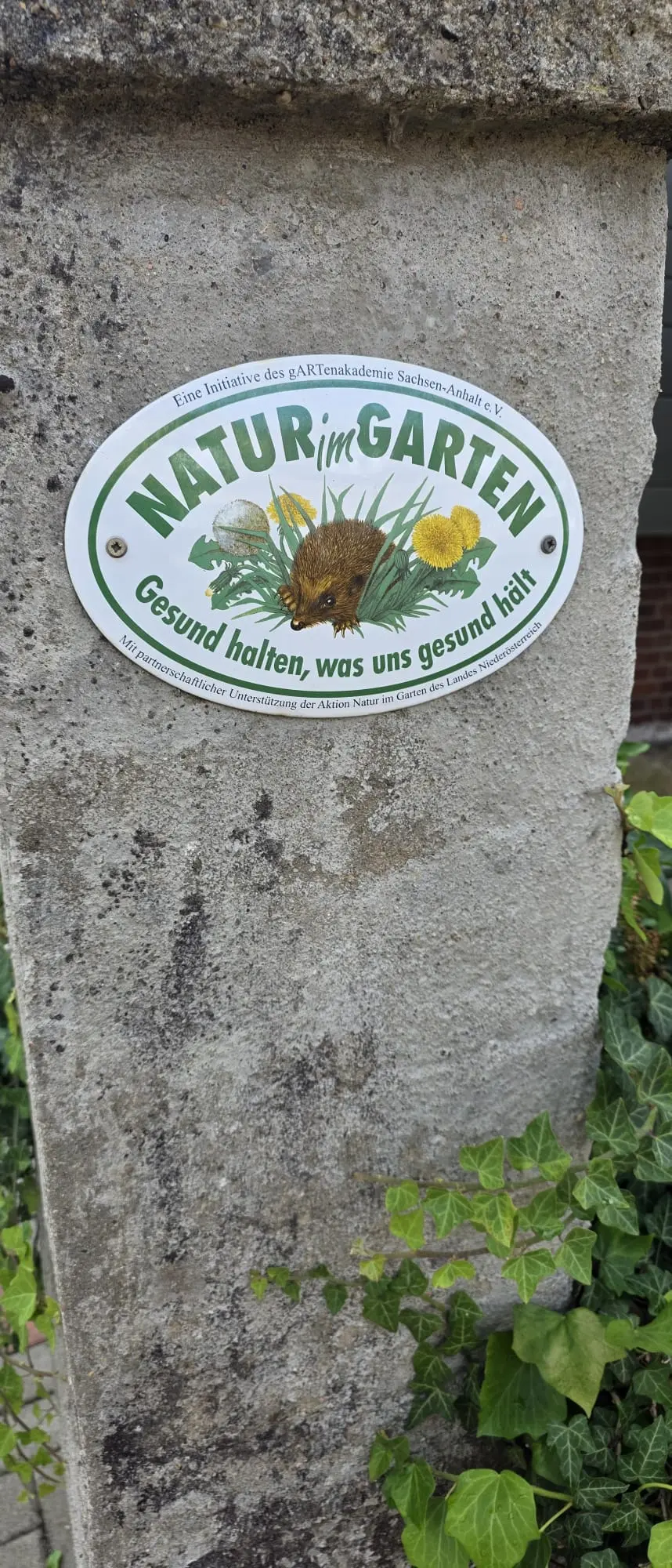 Haus und Garten der Ferienwohnung Zahna-Loft — Gartenschild mit Igel-Motiv und der Aufschrift „Gesund halten, was uns gesund hält“