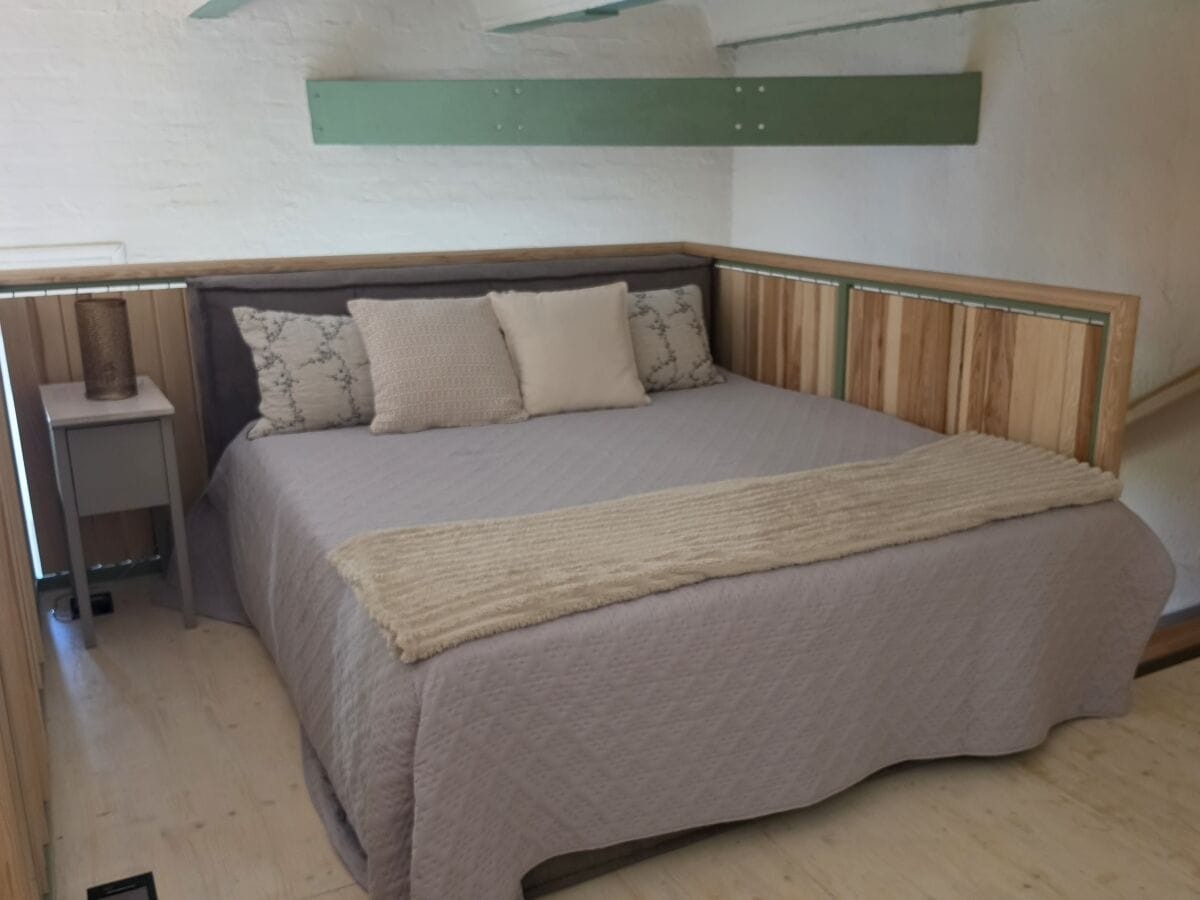 Boxspringbett auf der Schlafgalerie vor cremefarben getünchten Wänden, ohne Dachschräge