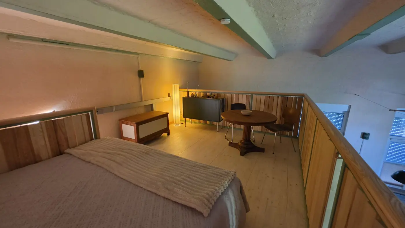 Schlafplatz auf der Galerieebene der Ferienwohnung Zahna-Loft — Doppelbett neben dem Sitzplatz mit rundem Tisch