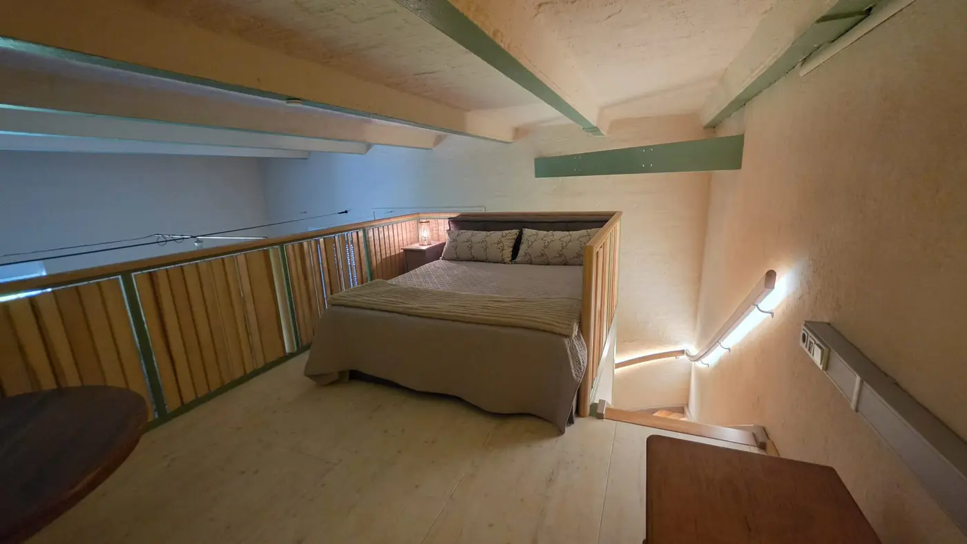 Schlafplatz auf der Galerieebene der Ferienwohnung Zahna-Loft — Doppelbett am Holzgeländer mit indirektem Lichtband